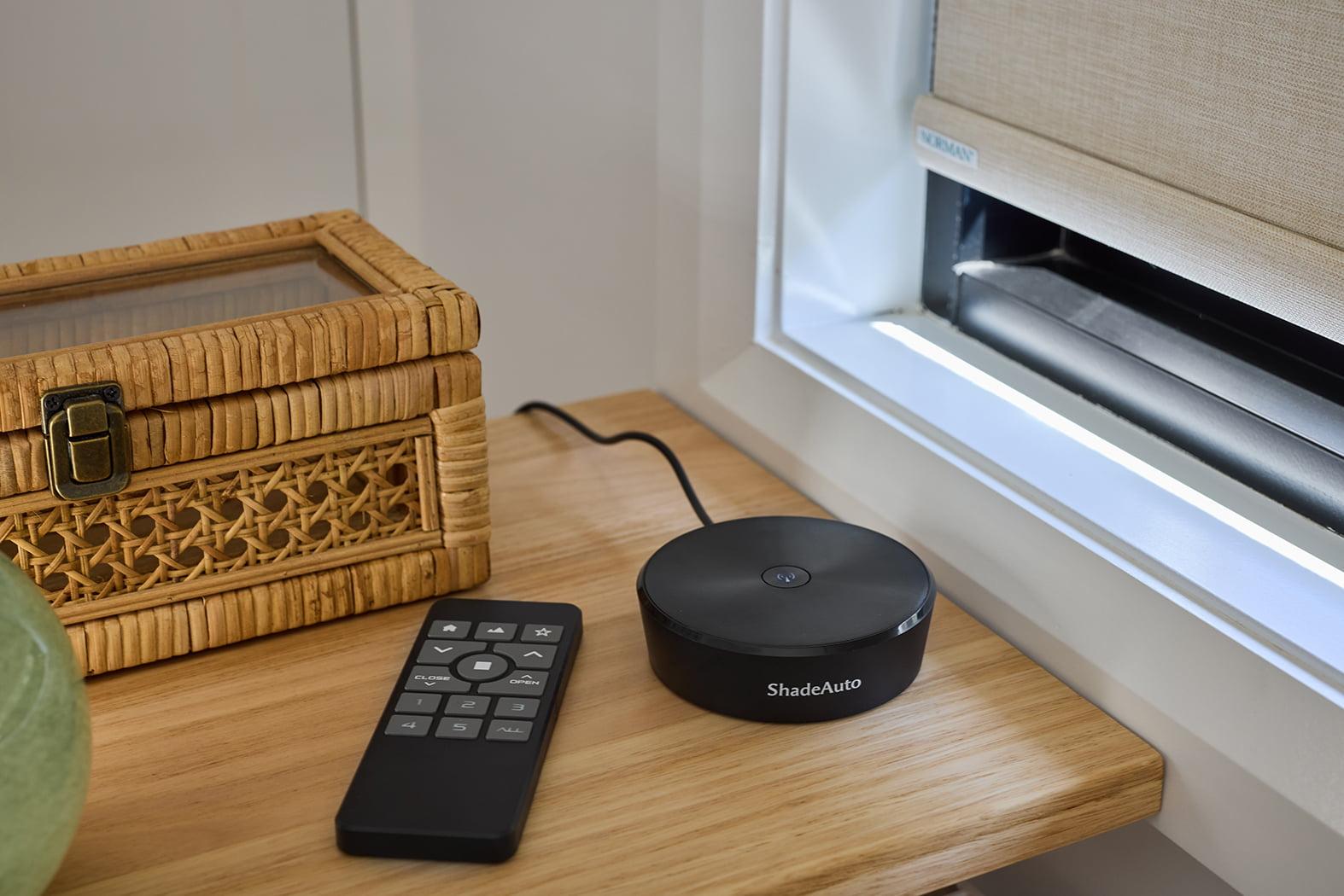 A motorisation hub and remote on a timber side table beside a window