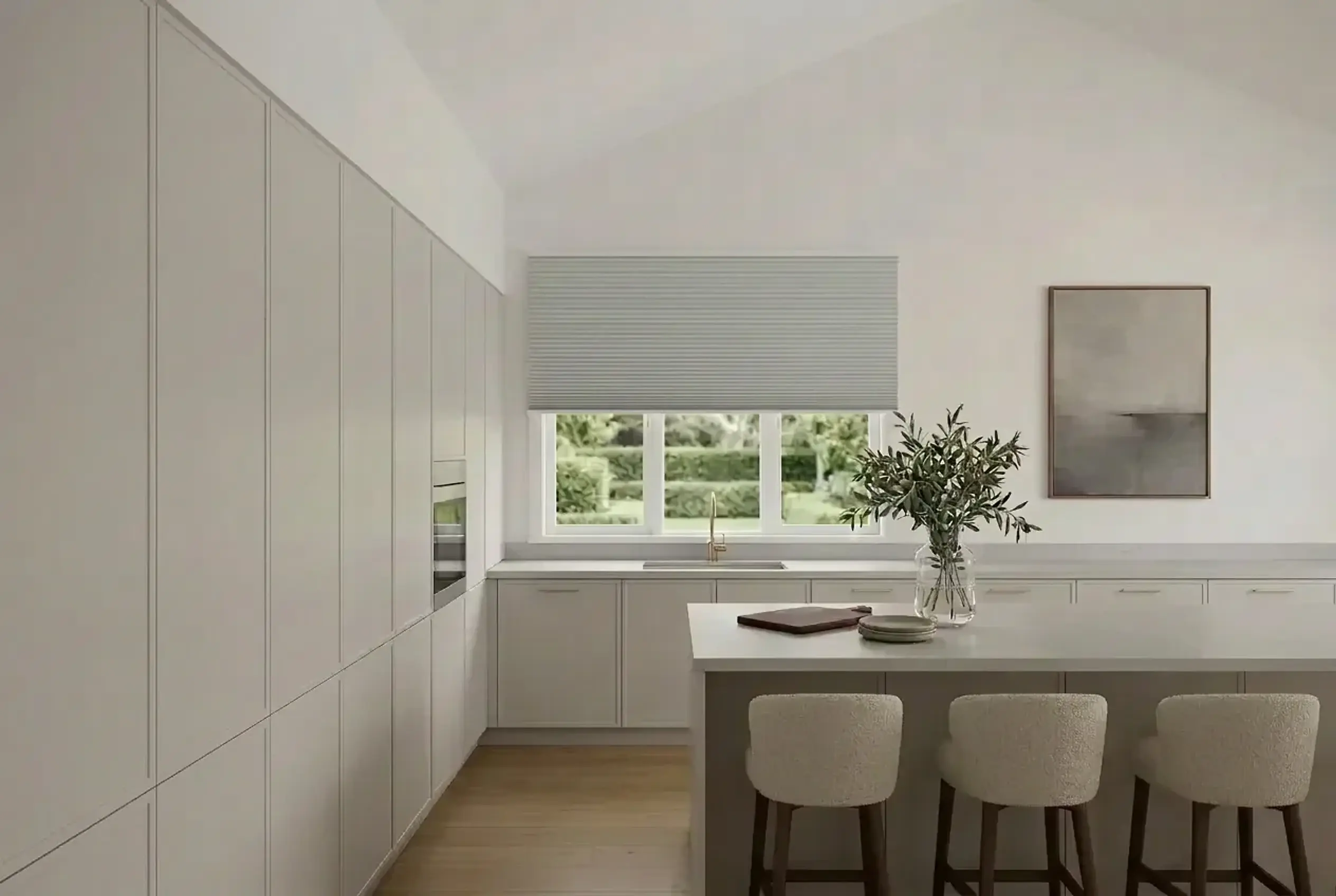 Pale grey honeycomb shade above a garden window in a bright white kitchen with Shaker cabinetry, a large stone-topped island and bouclé stools