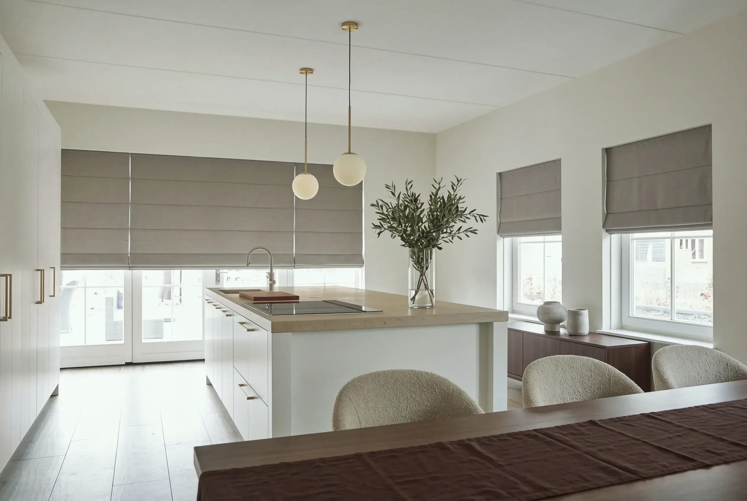 An open-plan living and dining room with sheer vertical panels across a glazed corner