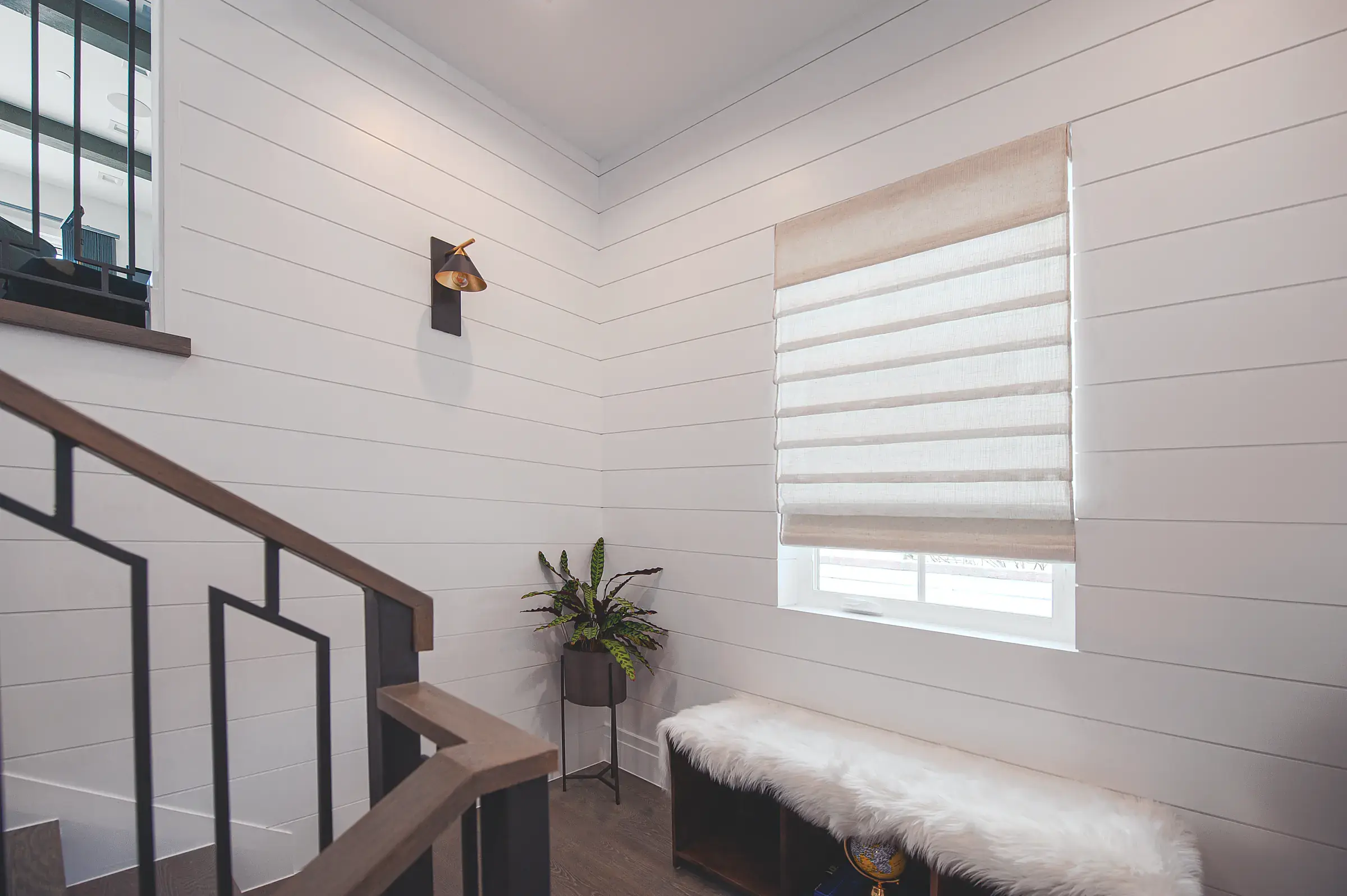 A white bedroom with louvred shutters at the window